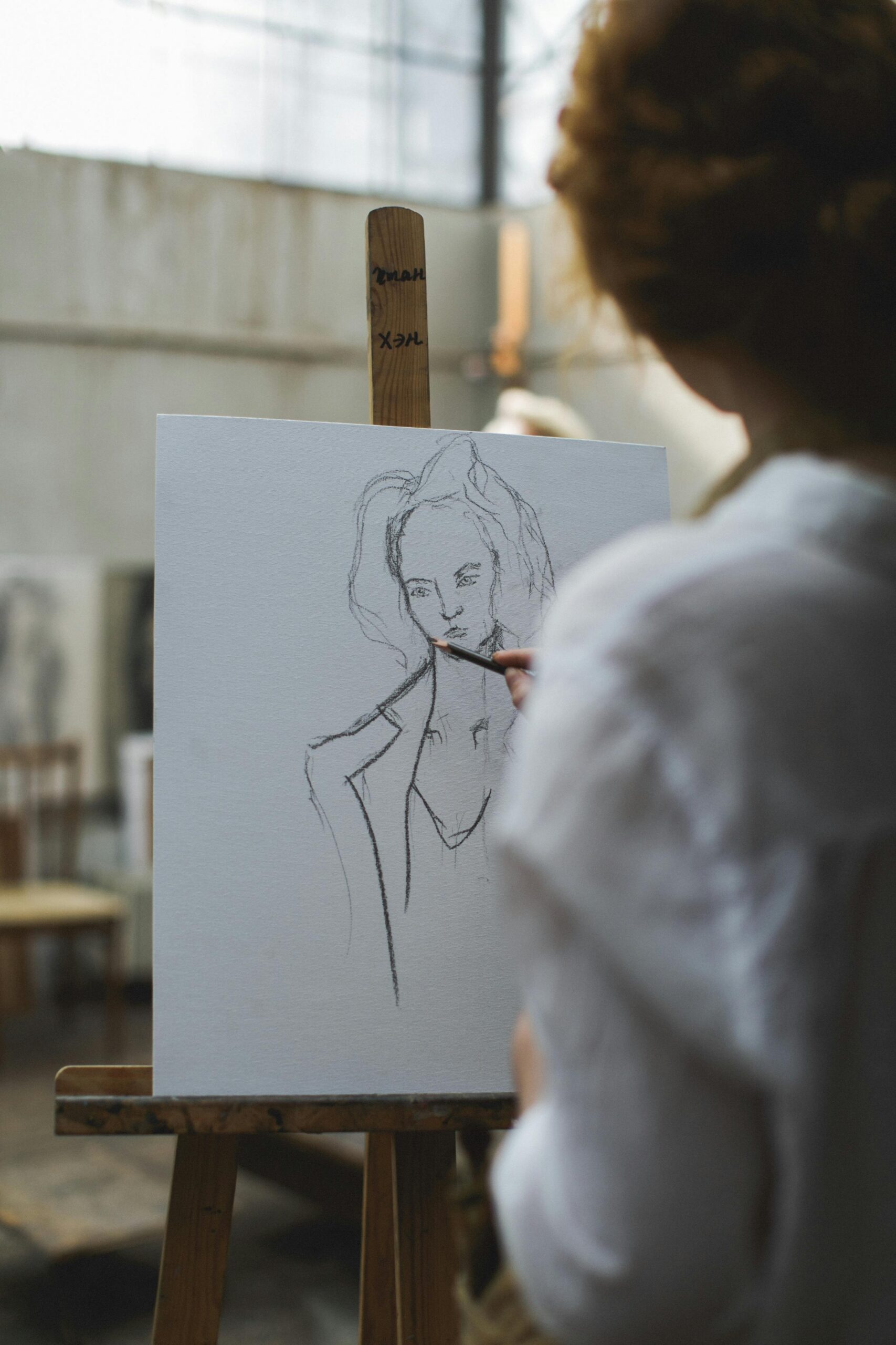 Artist sketching a portrait on canvas in an art studio, showcasing creativity and technique.